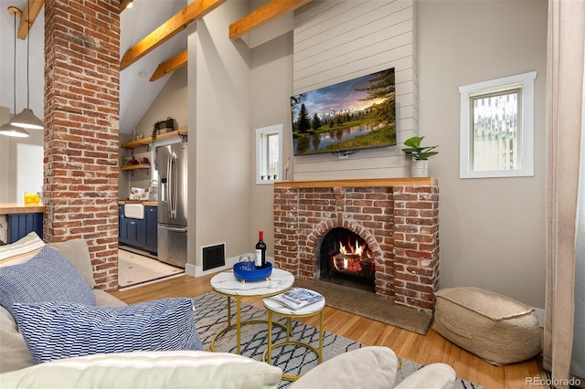 living area featuring a wealth of natural light, a brick fireplace, and wood finished floors