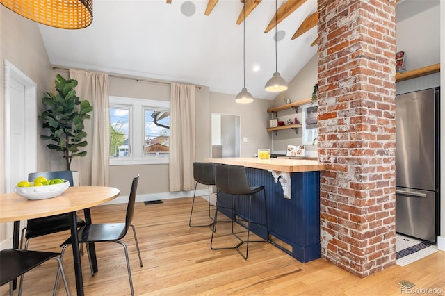 kitchen featuring light wood finished floors, wood counters, vaulted ceiling, and freestanding refrigerator