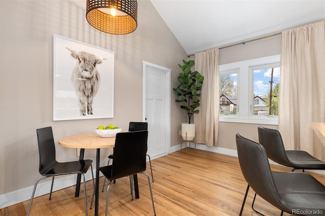 dining room featuring baseboards, high vaulted ceiling, and light wood-style floors