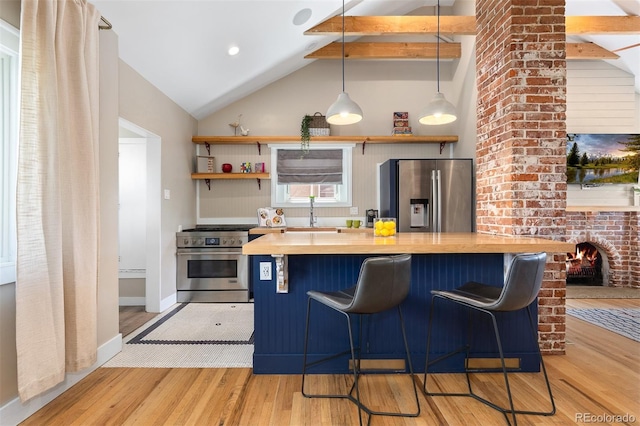 kitchen with open shelves, light wood-style flooring, a kitchen bar, lofted ceiling, and appliances with stainless steel finishes