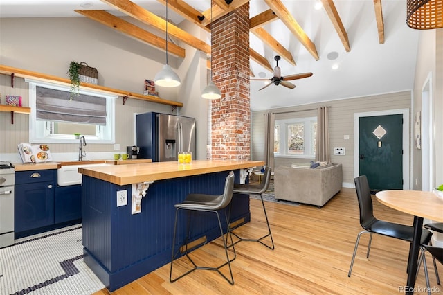 kitchen featuring stainless steel fridge with ice dispenser, open shelves, a sink, wood counters, and blue cabinetry