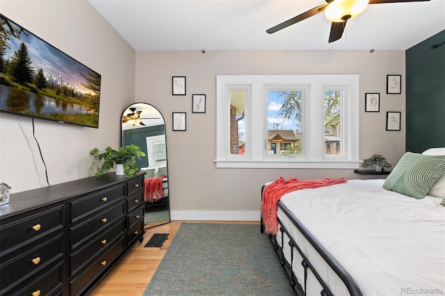 bedroom with baseboards, a ceiling fan, and light wood-style floors