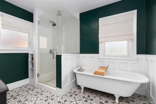 bathroom with tile patterned floors, a freestanding bath, a decorative wall, wainscoting, and a stall shower