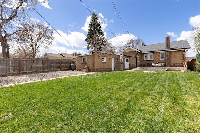 back of property with a fenced backyard, brick siding, a patio area, and a chimney