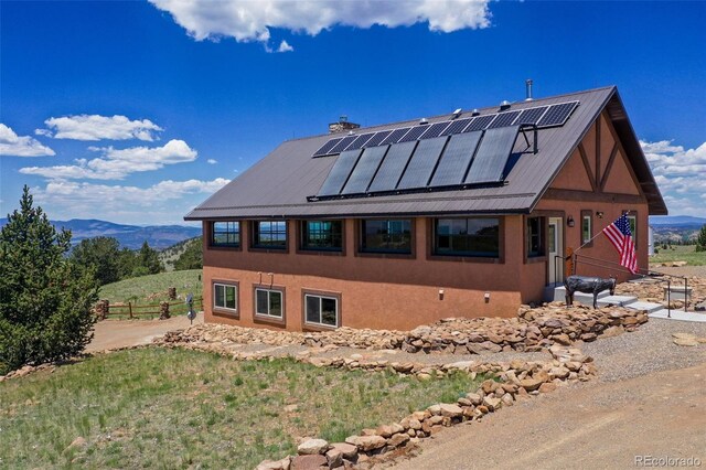 exterior space with roof mounted solar panels, a mountain view, and metal roof