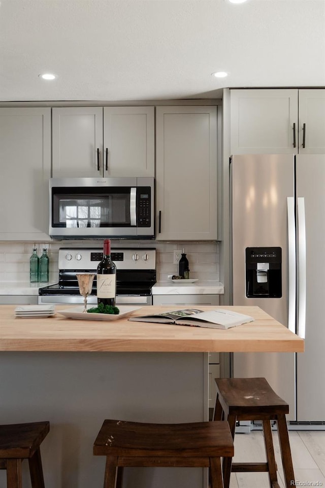 kitchen with stainless steel appliances, a breakfast bar, and wood counters