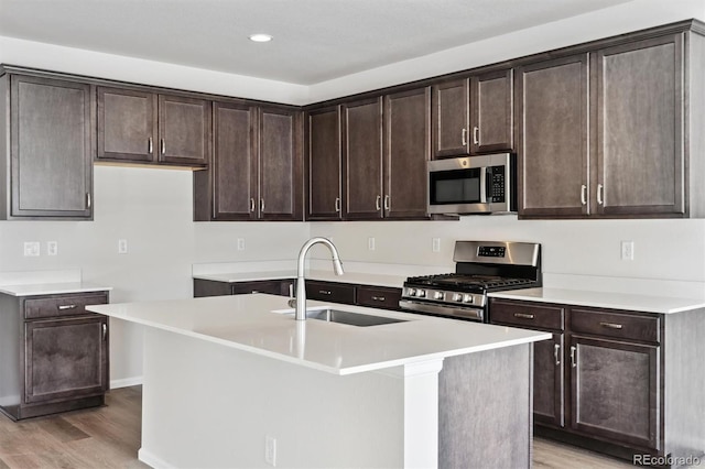 kitchen with sink, dark brown cabinets, an island with sink, and appliances with stainless steel finishes