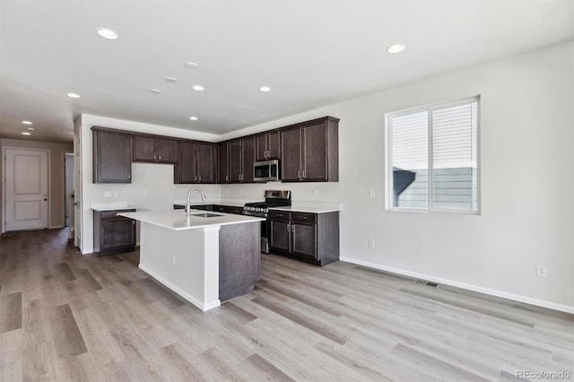 kitchen featuring dark brown cabinetry, stainless steel appliances, sink, and light wood-type flooring