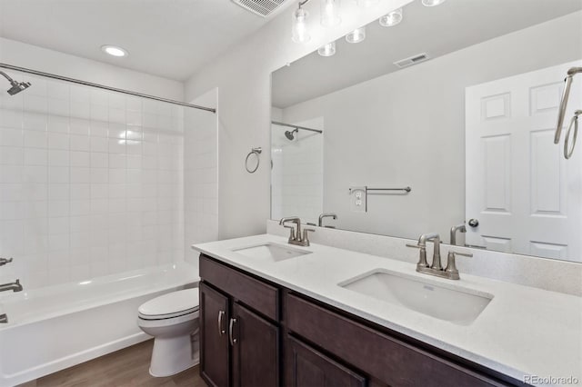 full bathroom with vanity, hardwood / wood-style flooring, tiled shower / bath combo, and toilet