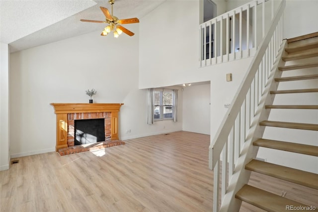 unfurnished living room featuring baseboards, ceiling fan, stairway, wood finished floors, and a fireplace