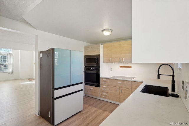 kitchen with light brown cabinets, stainless steel microwave, a sink, and black oven