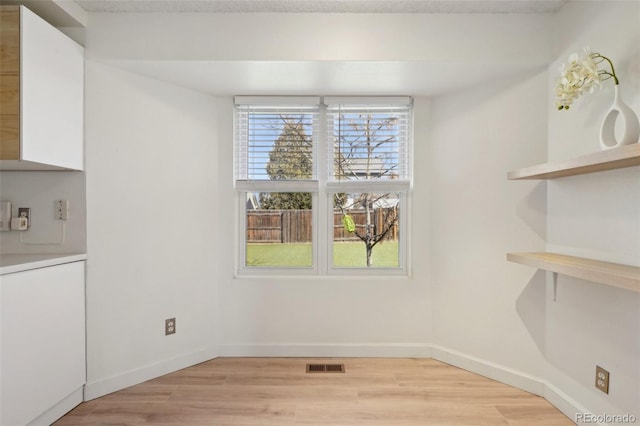 unfurnished dining area with light wood finished floors, baseboards, and visible vents