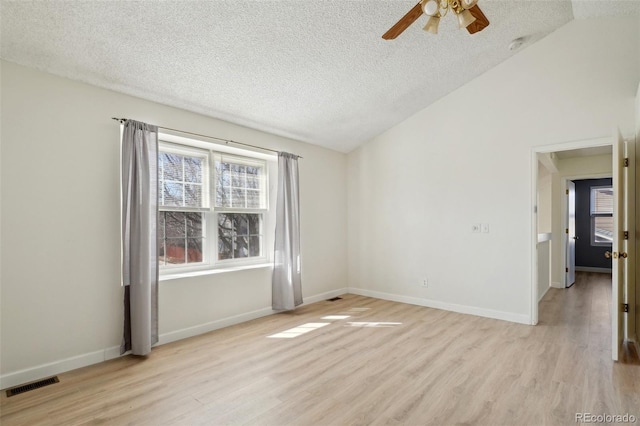 unfurnished room featuring light wood-style floors, baseboards, visible vents, and vaulted ceiling