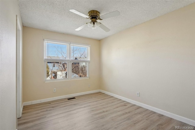 unfurnished room with light wood-style floors, visible vents, and a textured ceiling