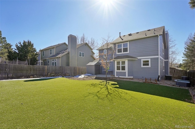 back of house featuring a fenced backyard, an outbuilding, a yard, a shed, and central AC