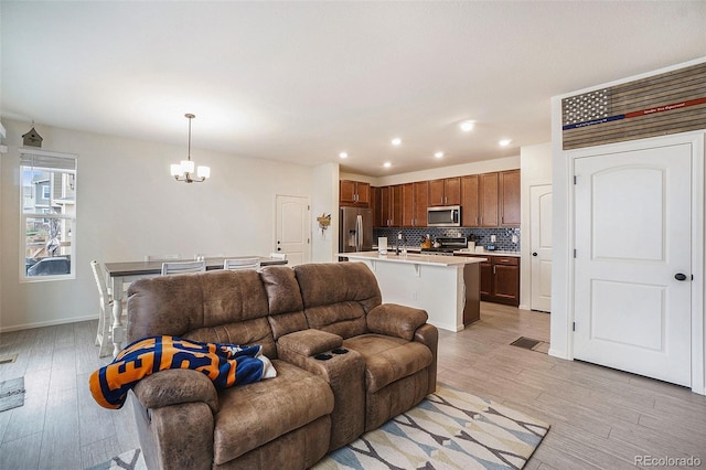 living room with light wood-type flooring, an inviting chandelier, and sink