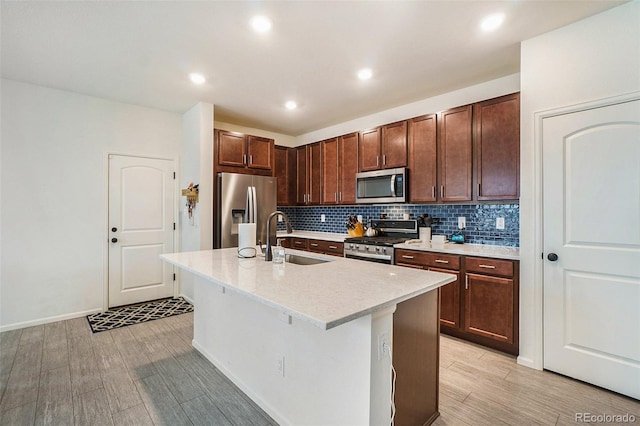 kitchen featuring a center island with sink, appliances with stainless steel finishes, tasteful backsplash, a breakfast bar, and sink