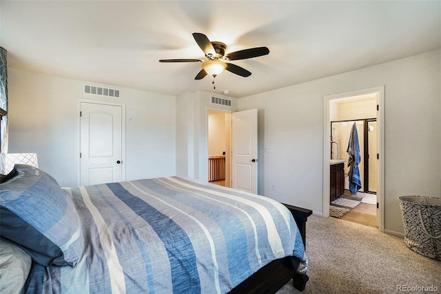 bedroom featuring ceiling fan, light colored carpet, and ensuite bathroom