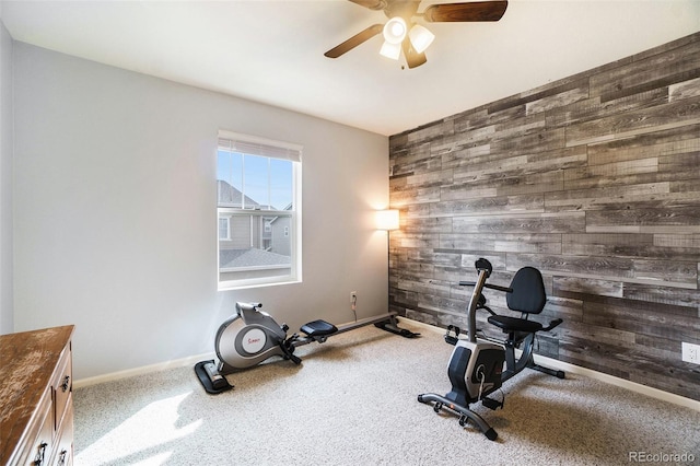 exercise area featuring ceiling fan, carpet, and wood walls