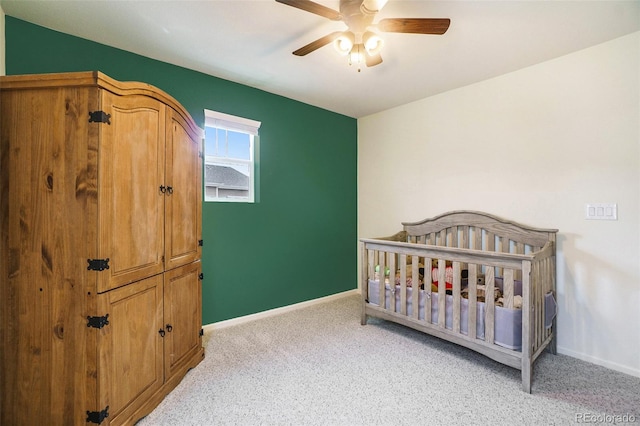 bedroom with ceiling fan, light carpet, and a crib