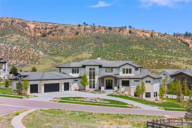 view of front of home featuring concrete driveway, an attached garage, a mountain view, and stone siding