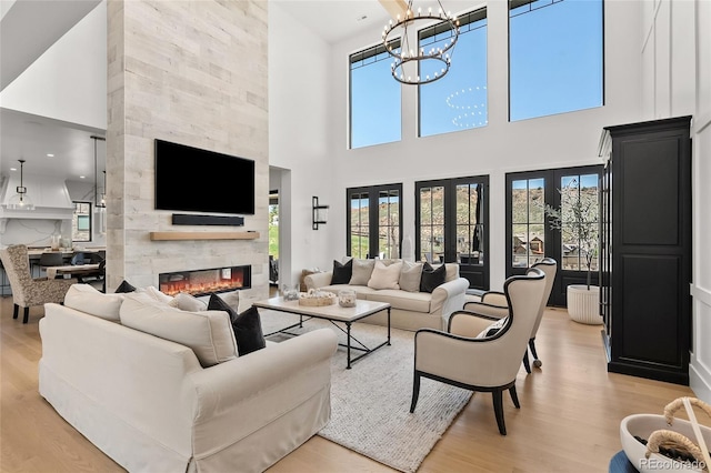 living area with a large fireplace, light wood finished floors, and a towering ceiling