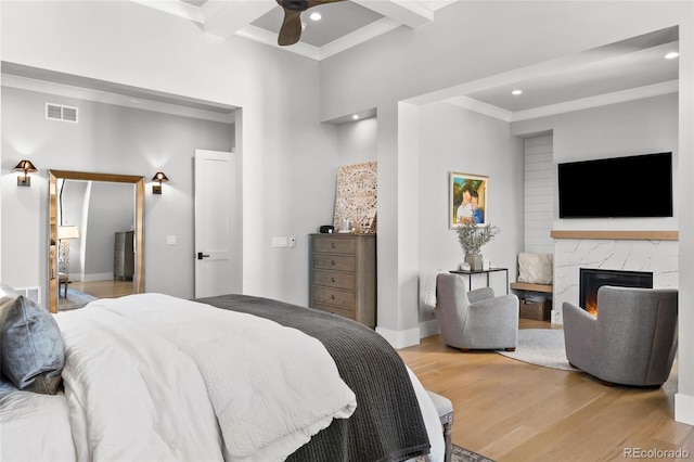 bedroom with visible vents, a fireplace, beam ceiling, light wood-style floors, and ornamental molding