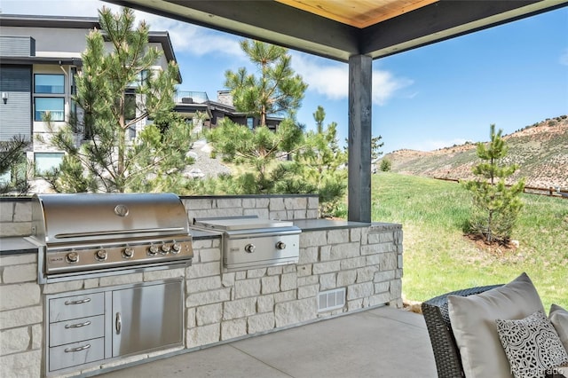 view of patio with area for grilling, a mountain view, and a grill