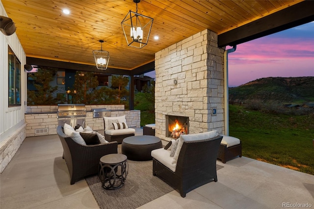 patio terrace at dusk featuring visible vents, grilling area, area for grilling, and an outdoor stone fireplace