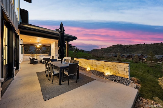 patio terrace at dusk with an outdoor living space, a mountain view, and outdoor dining space