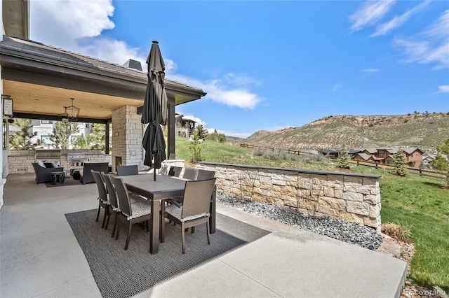view of patio / terrace featuring outdoor dining area, a mountain view, and area for grilling