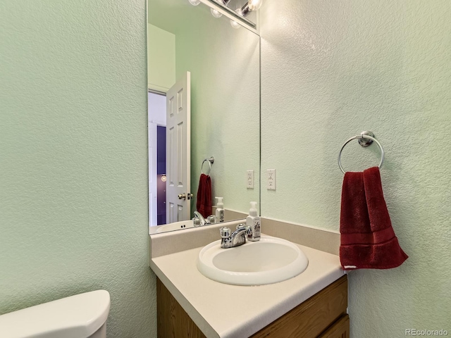 9832 Kenton Cir, Commerce City, CO 80022 - bathroom featuring vanity, toilet, and a textured wall