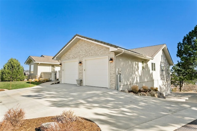 view of home's exterior with an attached garage, stone siding, and driveway