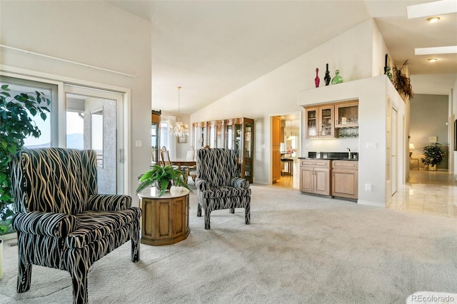 sitting room with a chandelier, light carpet, high vaulted ceiling, and wet bar