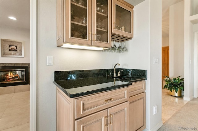 bar with indoor wet bar, recessed lighting, a multi sided fireplace, light tile patterned flooring, and a sink