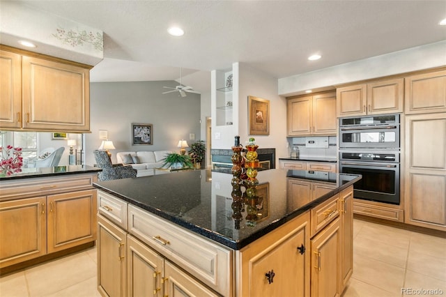 kitchen featuring dark stone counters, light tile patterned floors, double oven, a ceiling fan, and open floor plan