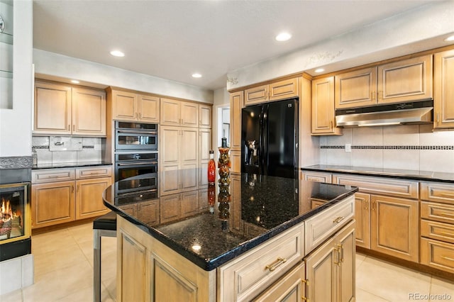 kitchen featuring black fridge, under cabinet range hood, light tile patterned floors, and double oven
