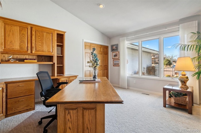 office featuring visible vents, vaulted ceiling, built in desk, light carpet, and baseboards