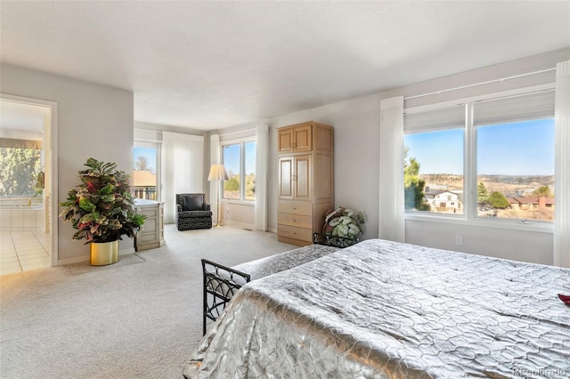 bedroom with ensuite bathroom, baseboards, and light colored carpet