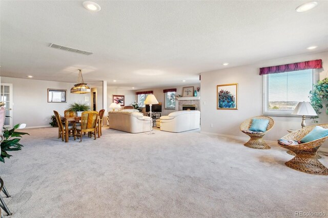 carpeted living room with visible vents, baseboards, a textured ceiling, recessed lighting, and a tile fireplace