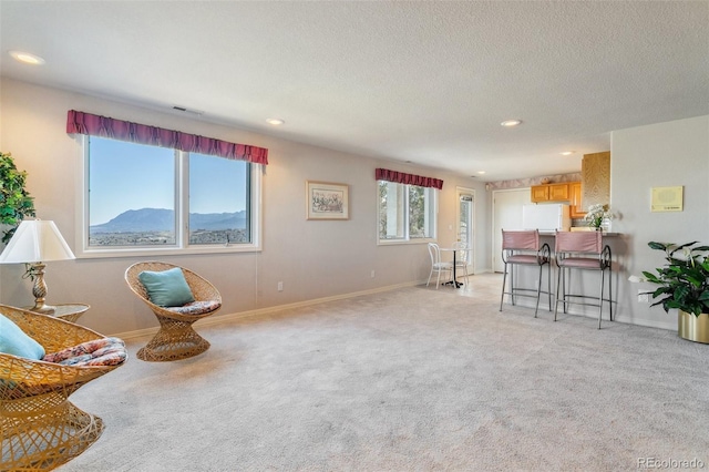 living area featuring light carpet, recessed lighting, baseboards, and a textured ceiling