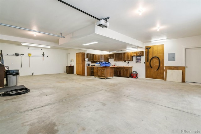 garage with a garage door opener, a workshop area, and electric panel