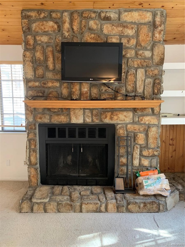 interior details with a stone fireplace, carpet floors, and wooden ceiling