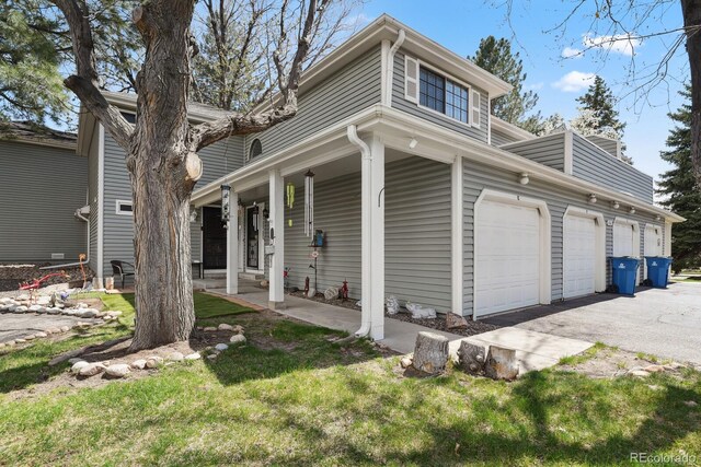 12622 E Warren Dr Unit E, Aurora, CO 80014 - view of side of property with covered porch, a yard, asphalt driveway, and a garage