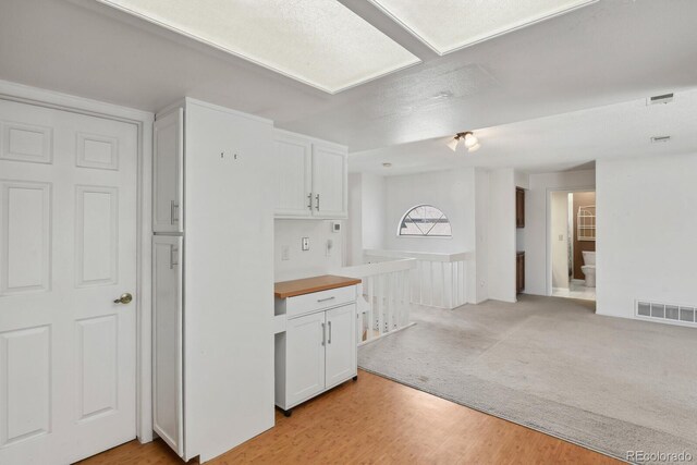 12622 E Warren Dr Unit E, Aurora, CO 80014 - kitchen featuring white cabinetry, light wood-style flooring, and visible vents