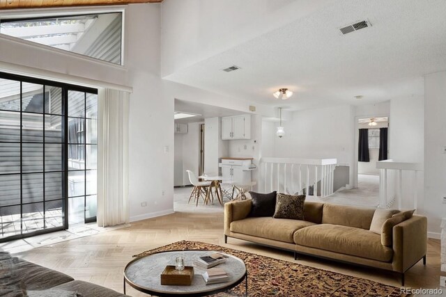 12622 E Warren Dr Unit E, Aurora, CO 80014 - living area featuring visible vents, baseboards, and a towering ceiling