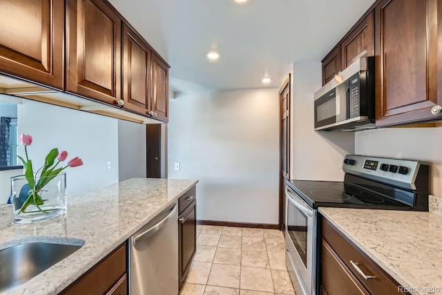 kitchen featuring appliances with stainless steel finishes, light stone countertops, sink, and light tile patterned floors