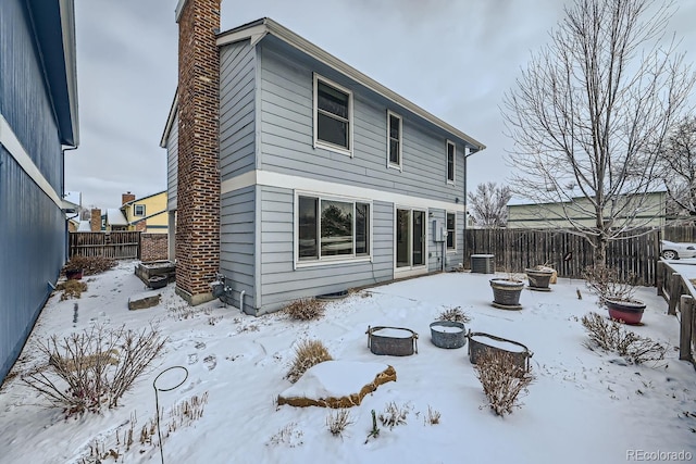 snow covered house featuring central air condition unit and a fire pit