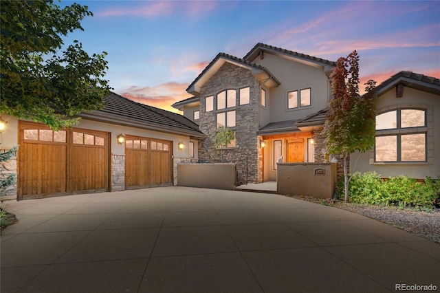 traditional-style home with stone siding, concrete driveway, and stucco siding