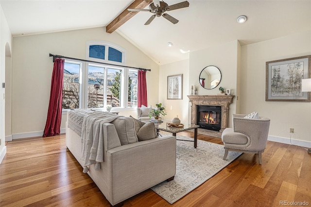 living room with arched walkways, beam ceiling, a high end fireplace, and light wood-style floors